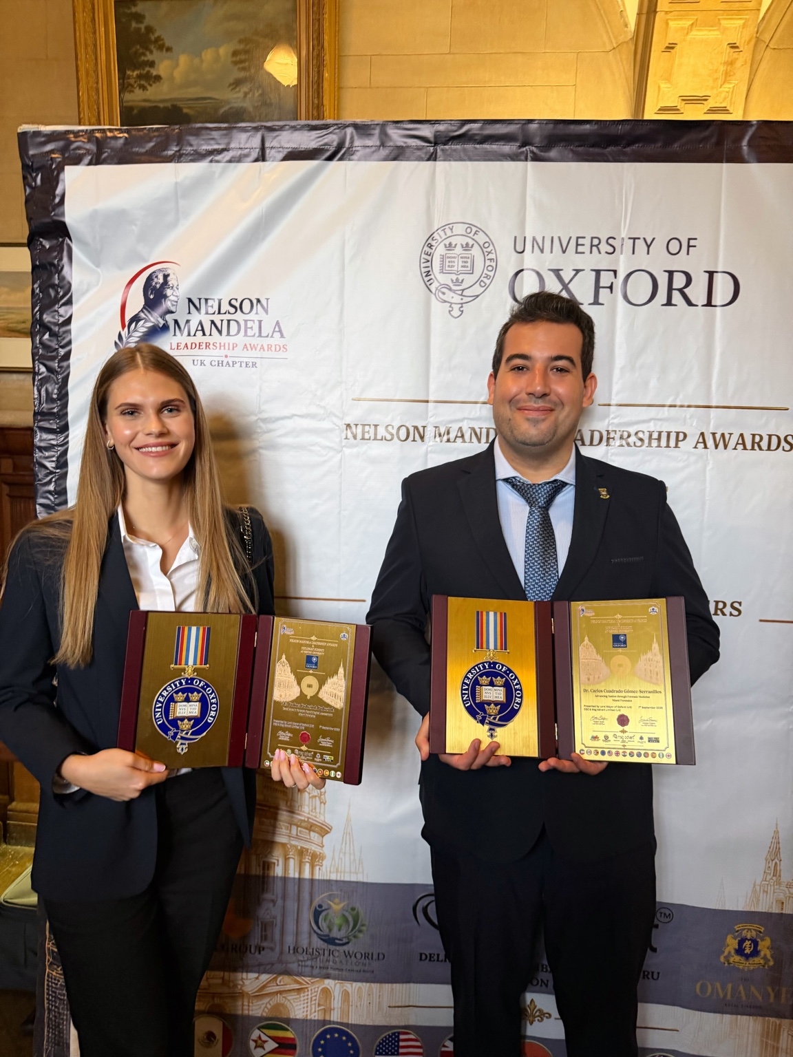 Dr. Carlos Cuadrado Gómez-Serranillos y Polina Poloziuk Poloziuk con sus reconocimientos en Oxford Town Hall